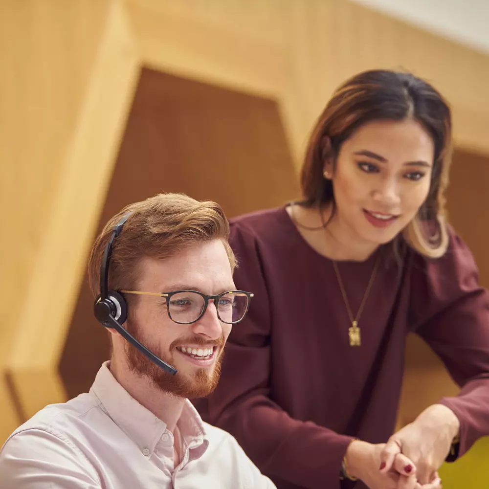 Twee klantenservice collega's kijken naar een beeldscherm buiten beeld.
